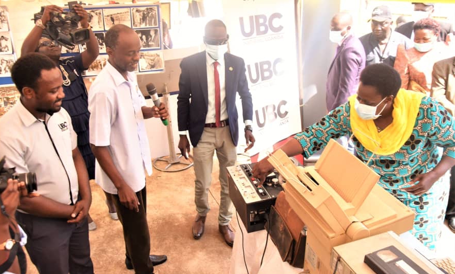 VP Alupo tests a UBC radio machine as technicians cheer her expertise